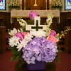 Pastel floral arrangement with a white cross in a purple vase