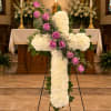White floral cross with pink roses on an easel in a church