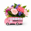 Pink floral arrangement in a pink school bus container