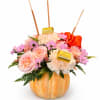 Pink and peach floral arrangement in a pumpkin container with chocolate bars