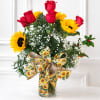 Red roses and yellow sunflowers in a glass vase with a sunflower ribbon