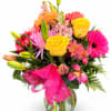 Bright mixed bouquet with yellow roses, pink gerberas, and lilies in a glass vase