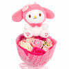 Pink plush character sitting on a bouquet of pink and cream roses