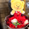 Yellow teddy bear in a bouquet of red and white roses