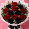 Bouquet of red and black roses with small white filler flowers, wrapped in white paper and tied with a black ribbon.