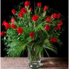 Red roses arranged in a clear glass vase with lush greenery