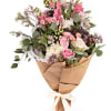 Bouquet of pink and white flowers wrapped in brown paper with a ribbon