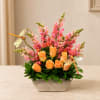 Orange roses and pink snapdragons in a rectangular vase with dragonfly picks