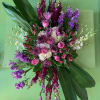 Large pink and purple floral arrangement with broad green leaves
