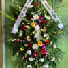 Large funeral wreath with mixed flowers and white condolence ribbons