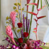 Tall tropical floral arrangement with pink and red blooms in a container