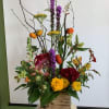Tall mixed floral arrangement in a wooden box with orange accents