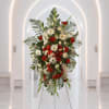 Standing floral spray with red and white flowers on a metal easel