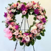 Large floral wreath of pink and purple blooms on a black stand