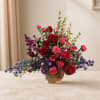Mixed bouquet of red, pink, purple, and blue flowers in a glass vase