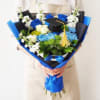 Bouquet of blue, white, and green flowers with a graduation cap topper