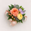 Small floral corsage with peach and yellow blooms and a pink ribbon