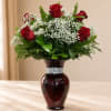 Red roses and white baby's breath in a dark glass vase