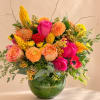 Bright mixed bouquet in a glass vase with pink, orange, and yellow blooms