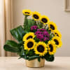 Sunflower arrangement with purple flowers in a gold container
