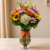 Colorful mixed bouquet in a clear glass vase with a ribbon bow