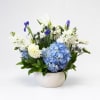 Blue and white floral arrangement in a white bowl vase