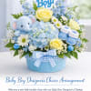 Blue and yellow baby-themed flower arrangement with a teddy bear and booties