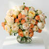 Peach and cream roses arranged in a clear glass vase