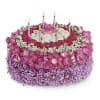 Round pink and purple floral cake with lit candles
