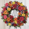Colorful floral wreath on a black easel with roses, lilies, and daisies