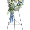 Heart-shaped floral wreath on a standing easel with blue and white flowers