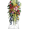 Tall standing floral spray with mixed colorful blooms on an easel