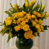 Yellow roses and tulips arranged in a glass vase