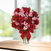 Red roses and pink alstroemeria in a clear glass vase with a red bow
