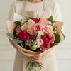 Layered roses in blush, peach, coral and deep pink form the heart