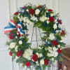 A large circular sympathy wreath in red, white &amp; blue, designed as