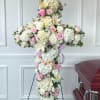 A white and blush cross-shaped funeral arrangement arranged for a service or