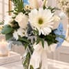 Bouquet of white daisies, roses, and blue hydrangeas in a glass vase