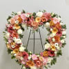 Heart-shaped floral wreath with pink, peach, white, and yellow blooms