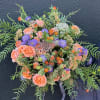Round bouquet of peach roses and purple flowers with airy greenery.