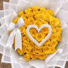 Bouquet of yellow roses wrapped in white paper with a white heart decoration