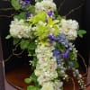 Tall floral arrangement with white, green, and purple blooms
