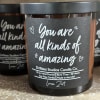 Black jar candle with a label reading "You are all kinds of amazing"
