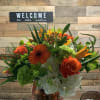 Orange is the focal in roses, gerbera daisies and lilies beautifully arranged