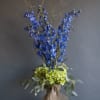 Tall blue flower arrangement with green hydrangeas in burlap wrap