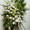 Large white and green funeral spray with roses and orchids on a stand