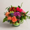 Mixed bouquet in a striped glass vase with pink roses and orange carnations