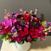 Bouquet of red roses and purple flowers in a white vase