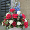 Basket arrangement of red carnations, white roses, and blue delphinium