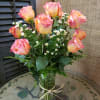 Pink and yellow roses with small white daisies in a glass vase
